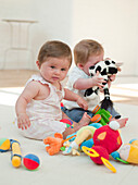 Baby girls playing with soft toys