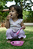 Baby girl in garden eating
