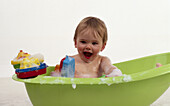 Baby girl in plastic green bubbly bath