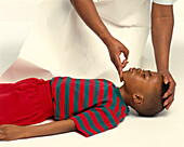 Tilting unconscious little boy's head back to free airway