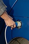 Woman plugging power cable in to an electric car