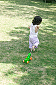 Baby girl in garden pulling toy on a string
