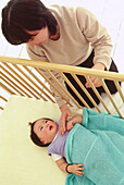 Woman standing beside a cot