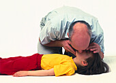 Man demonstrating mouth to mouth resuscitation on child