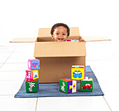 Boy standing inside a cardboard box holding a cube