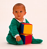 Baby seated with two fabric multi-coloured cubes