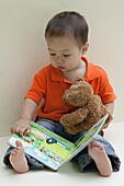 Baby boy sitting and reading a book