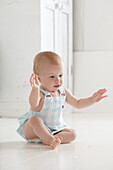 Baby girl sitting on floor hands in the air