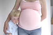 Preschool boy with head against pregnant mother's stomach