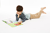 Boy in stripey top reading lying down