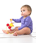 Baby girl sitting playing with pull along toy duck