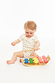 Baby in playsuit sitting with xylophone