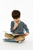 Boy in stripey top sitting and reading