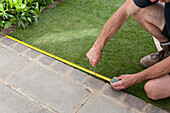 Using a tape measure to measure shape for a new lawn design