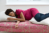 Young pregnant woman with pillows under head and legs