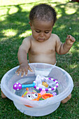 Baby boy in garden playing with toys in water