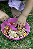 Baby girl in garden touching mixed bean salad