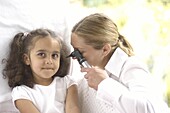 Doctor examining girl's ear with an otoscope
