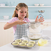 Girl sifting flour into a mixing bowl