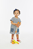 Little girl in stripey dress playing with push along toy