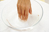 Hand submerging nails in liquid