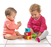Baby girl and toddler girl playing with building blocks