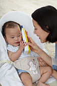 Mother holding toy phone against face of baby boy
