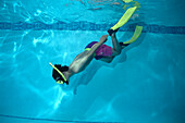 Boy in a swimming pool wearing fins, snorkel and mask