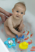 Baby girl in bath with toys