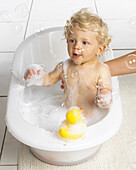 Boy in bath tub catching bubbles