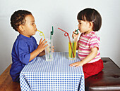 Boy and girl drinking through straws