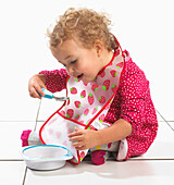 Girl holding bowl and eating from spoon