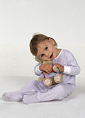 Girl in her pyjamas cuddling a soft toy