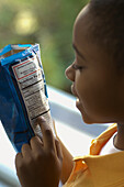 Boy reading nutrition label on bag of crisps