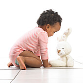 Girl kneeling towards a toy rabbit