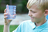 Boy looking at container filled with rainwater