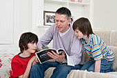 Father reading brochure to sons in living room