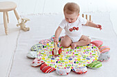 Baby boy sitting on play mat