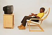 Boy sitting in armchair watching television