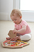 Baby girl sitting on floor playing with educational toy