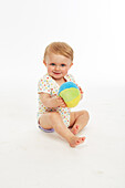 Baby in playsuit sitting with ball