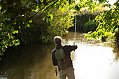 Man casting fly fishing line into a river