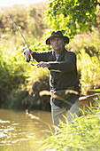 Man casting fly fishing pole at a river