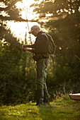 Man preparing fly fishing pole at riverbank