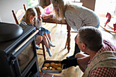 Family removing fresh hot biscuits from oven