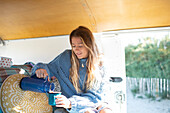 Young woman pouring coffee inside camper van