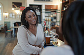 Happy woman enjoying wine with friend in bar