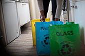 Woman sorting recycling into bags in kitchen