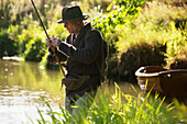Man preparing fly fishing line at a river