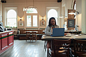 Businesswoman using a laptop at cafe table